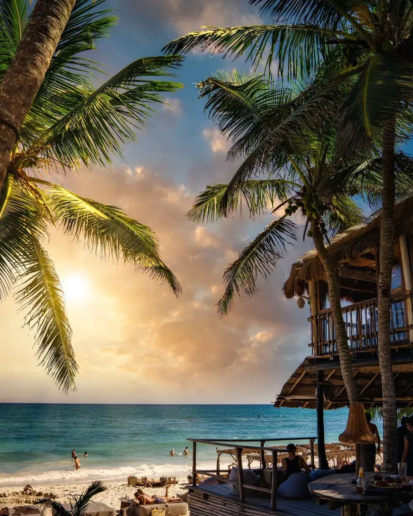 Famille profitant d’une plage tropicale à Cancún, avec palmiers, tente en bambou et mer turquoise
