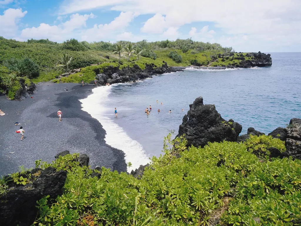 Petite plage sur la côte est de la Réunion avec familles se baignant dans l’océan