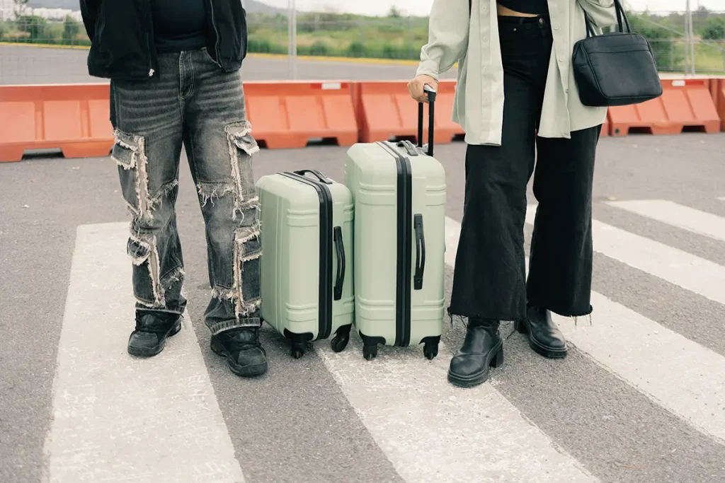Deux voyageurs avec des valises vert clair sur un passage piéton